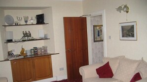 A compact living space with a kitchenette, a white sofa, and a patterned carpet. - Mardon Guest House (Inverness)