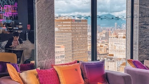 A modern lounge area with a sofa set, a glass coffee table, and a view of a cityscape through large windows. - Aloft Taipei Zhongshan (Taipei)