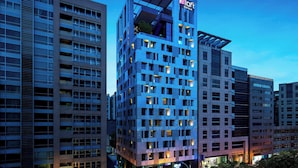A modern hotel building with multiple floors, large windows, and a prominent rooftop terrace. - Aloft Taipei Zhongshan (Taipei)