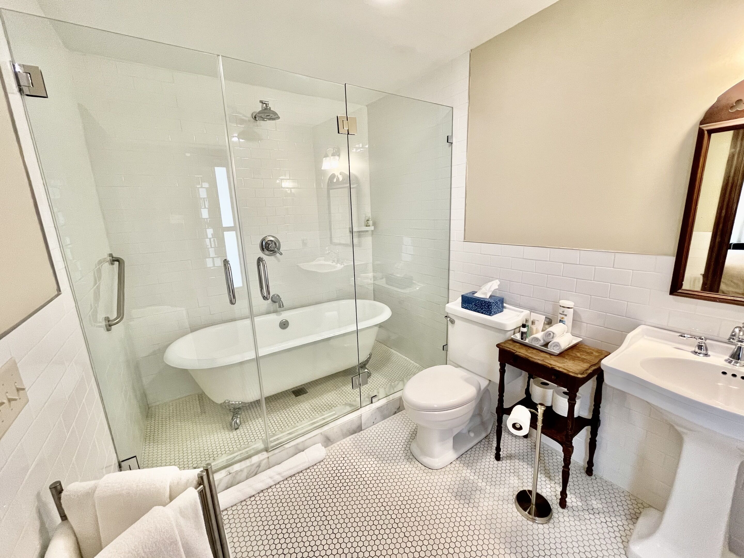 A modern bathroom with a glass-enclosed shower, a freestanding bathtub, a toilet, and a vanity with a mirror.
