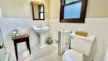 A bathroom with a white sink, toilet, and a small table with toiletries.