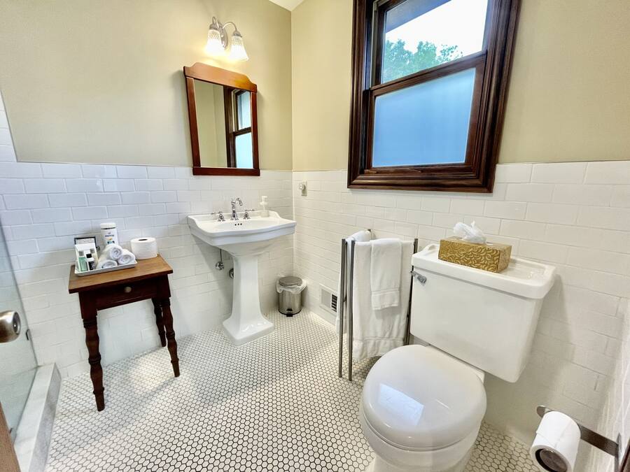 A bathroom with a white sink, toilet, and a small table with toiletries.