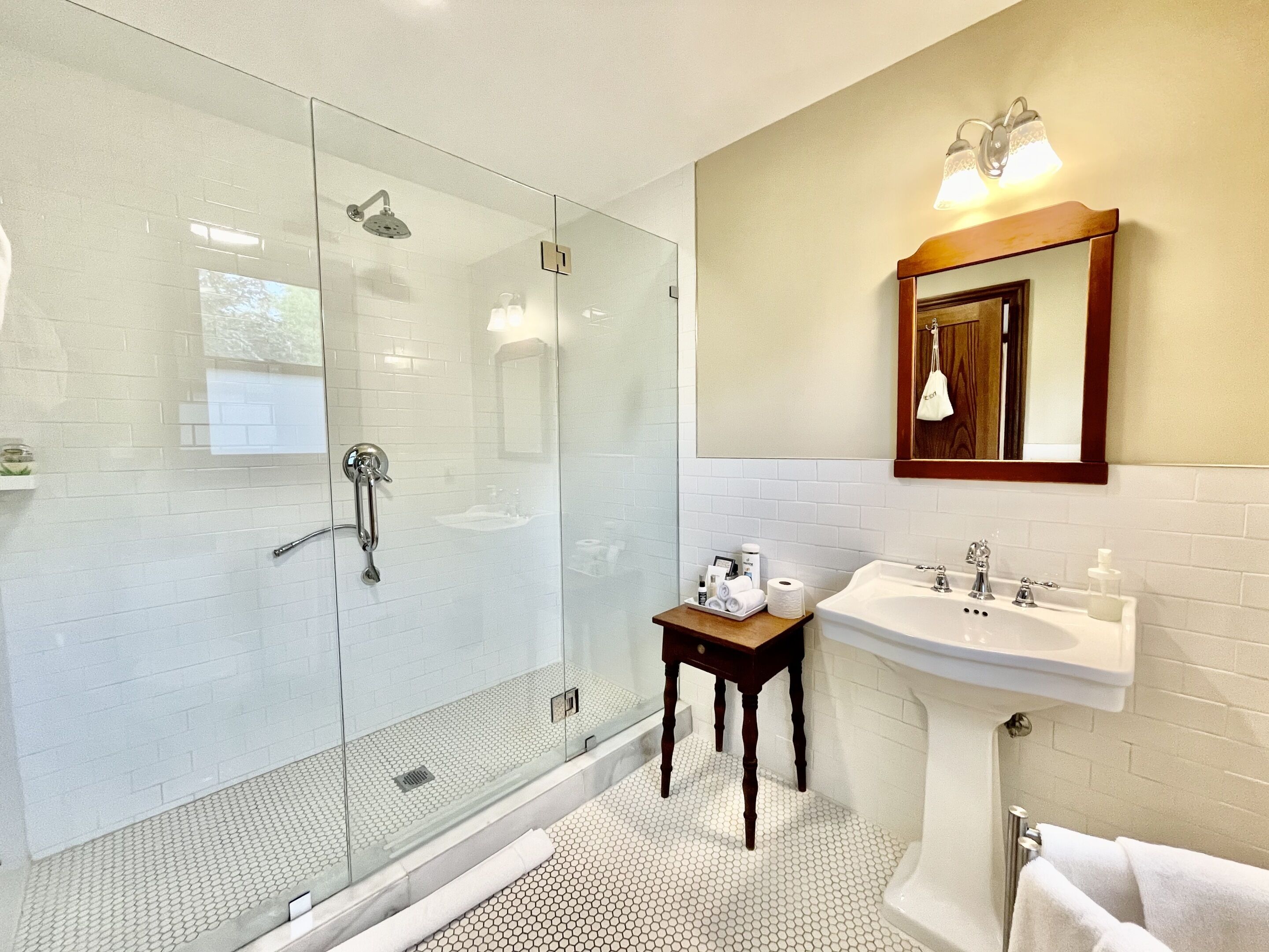A modern bathroom with a glass-enclosed shower, a wooden vanity with a sink, and a mirror above the vanity.