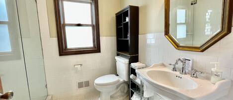 A bathroom with a toilet, sink, and shower.