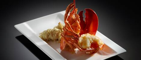 A lobster dish on a white plate with a dark background.