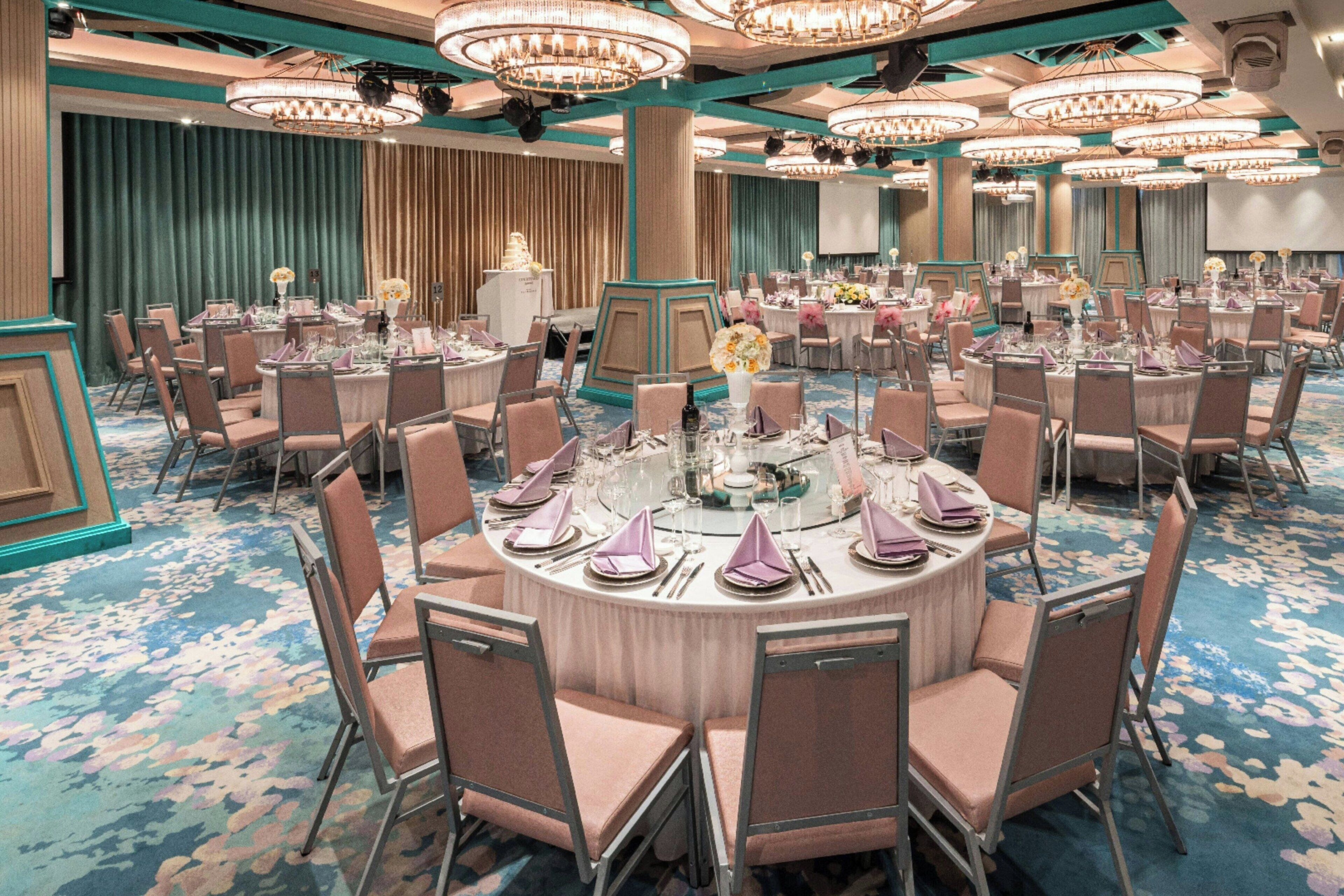 A large conference room with round tables, chairs, and chandeliers.
