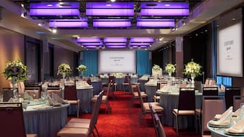 A conference room with round tables, chairs, and a large screen displaying 'COURTYARD Marriott'.