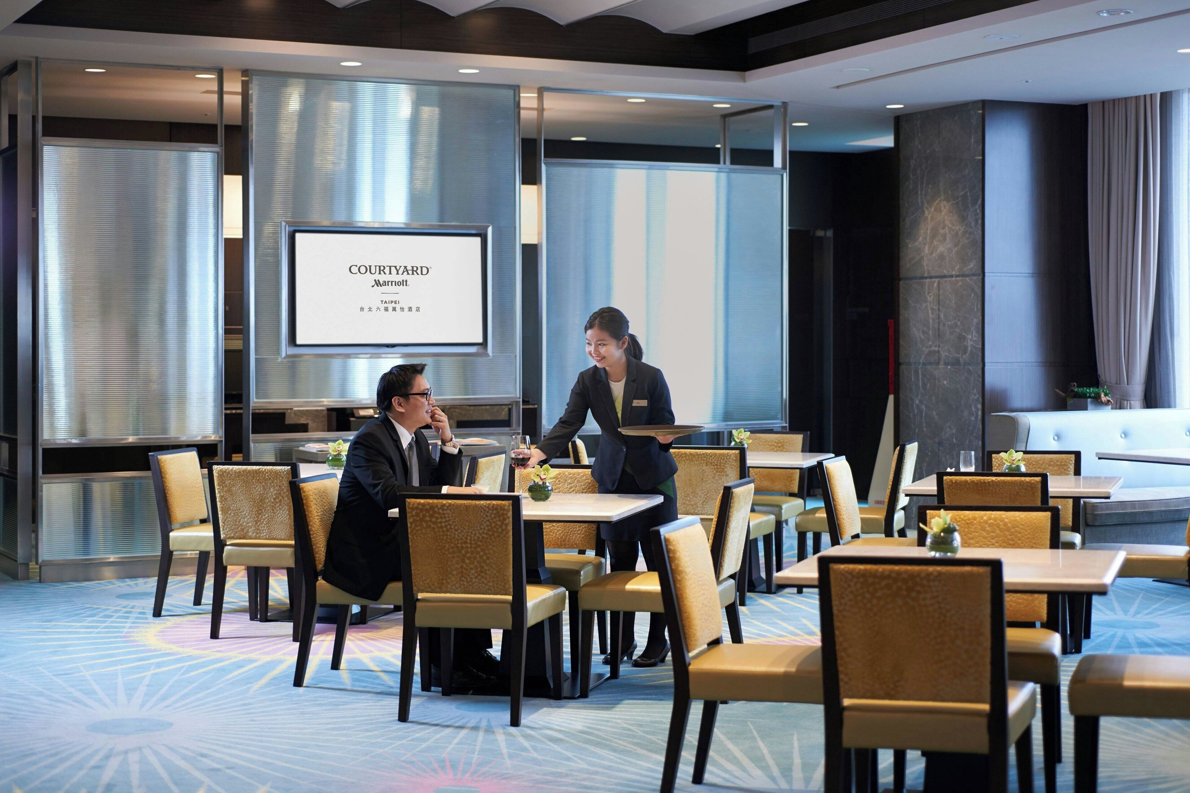 A conference room with a large screen displaying "COURTYARD Marriott" and a person standing near the screen.