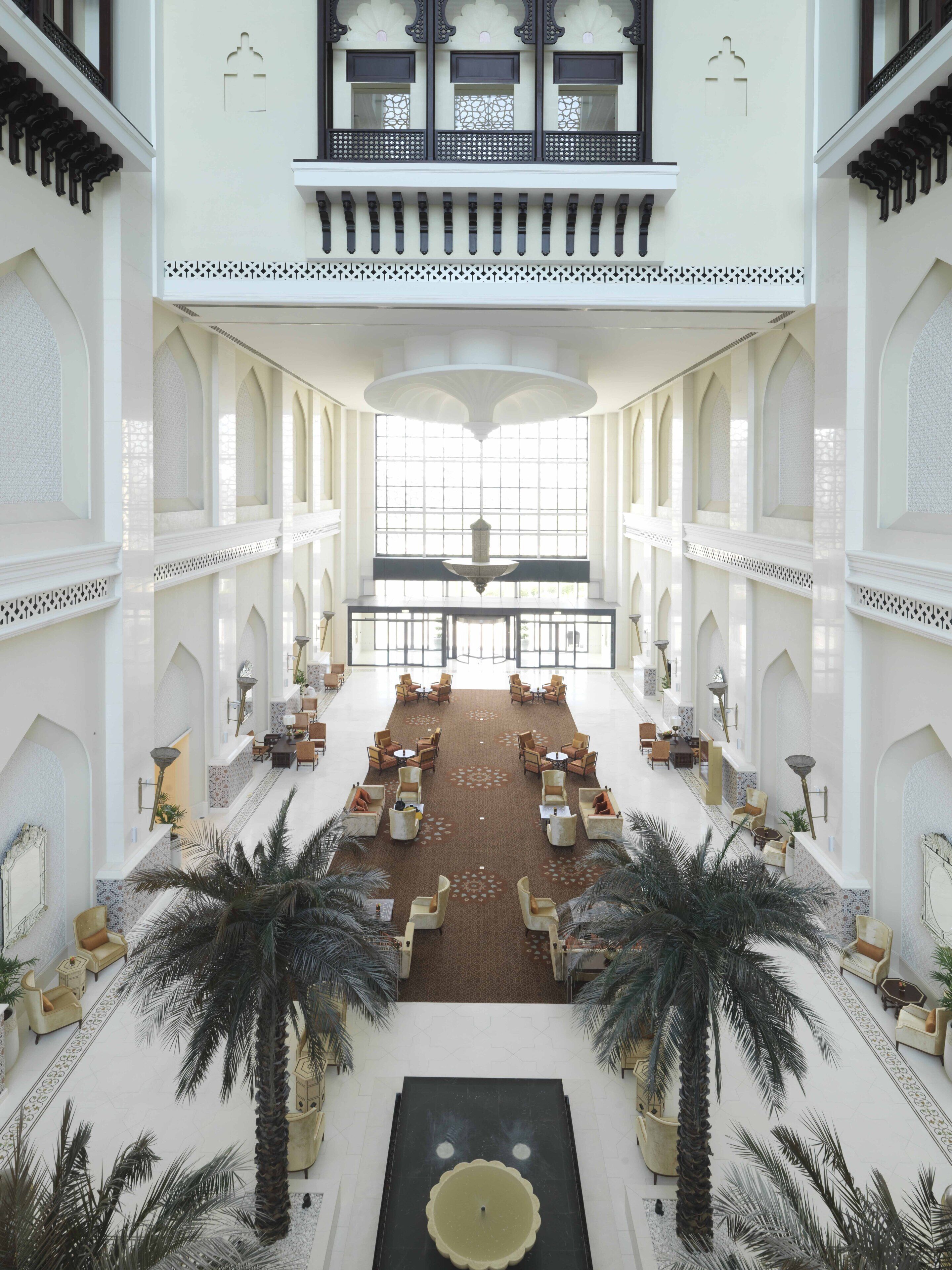 A spacious lobby with a central fountain, seating areas, and palm trees.