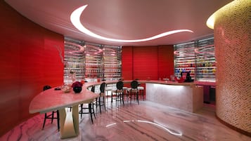 Un interior moderno con una mesa de comedor curva, una zona de bar y una pared de acento roja.