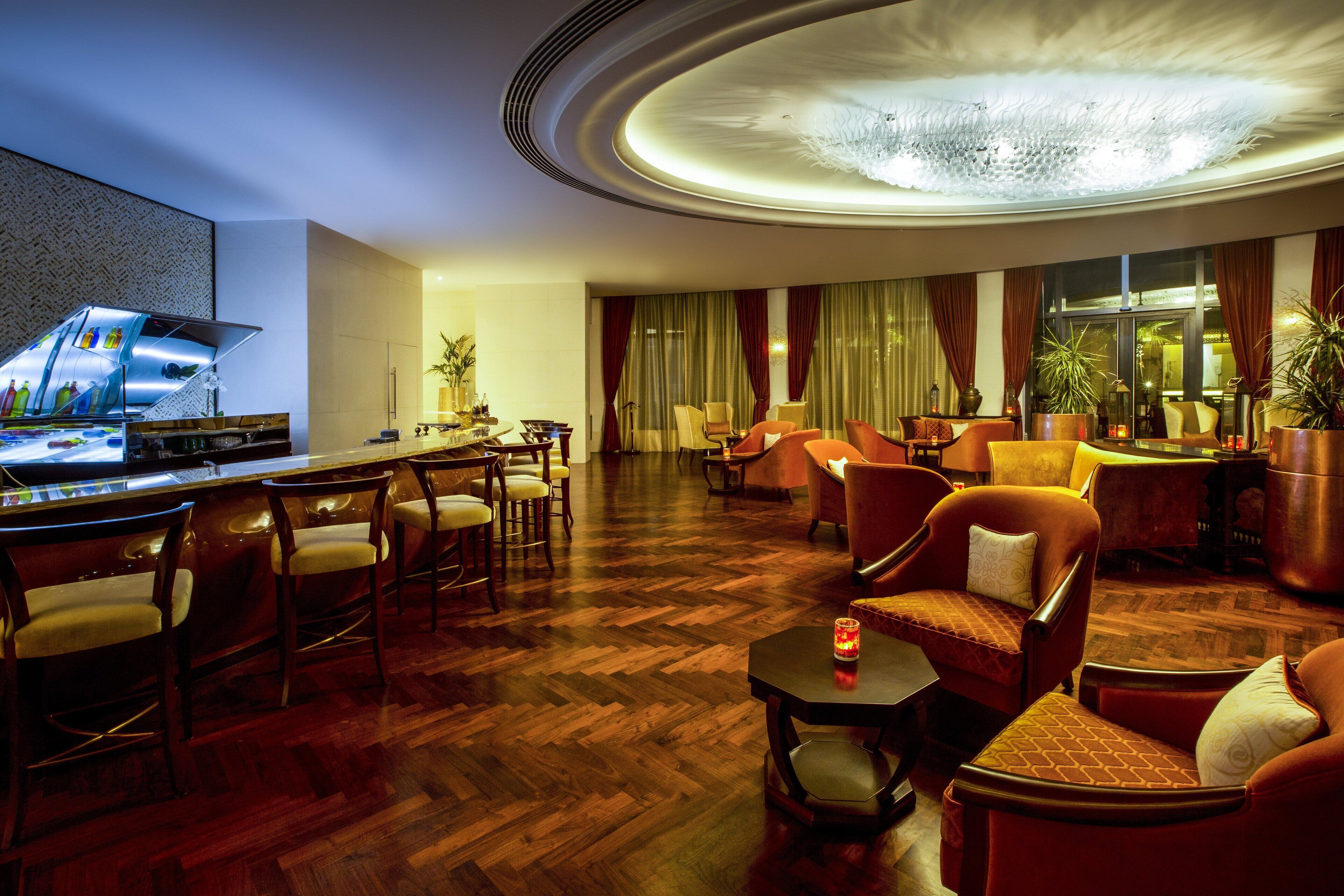 Un vestíbulo de hotel con zona de bar, asientos y un techo decorativo.