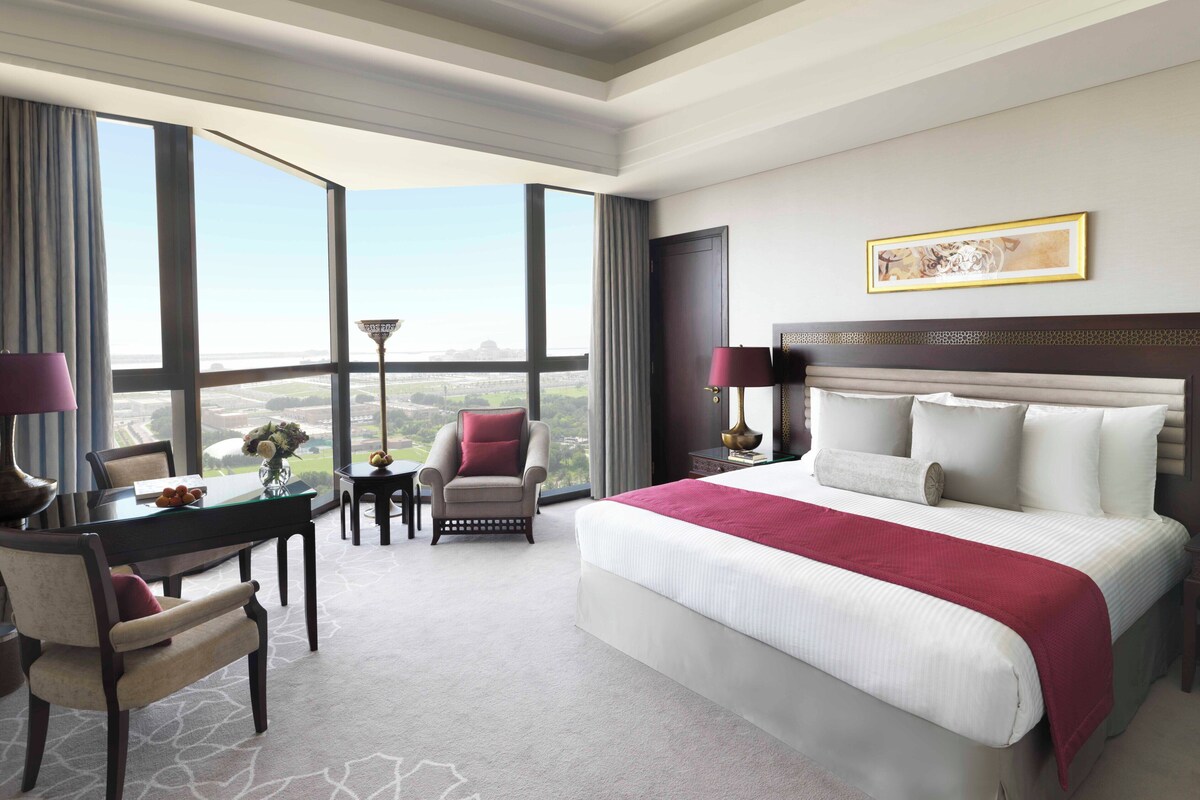 Une chambre d’hôtel avec un grand lit, un bureau, une chaise et une vue sur la ville.