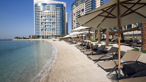 Una località balneare con lettini, ombrelloni e alti edifici sullo sfondo.