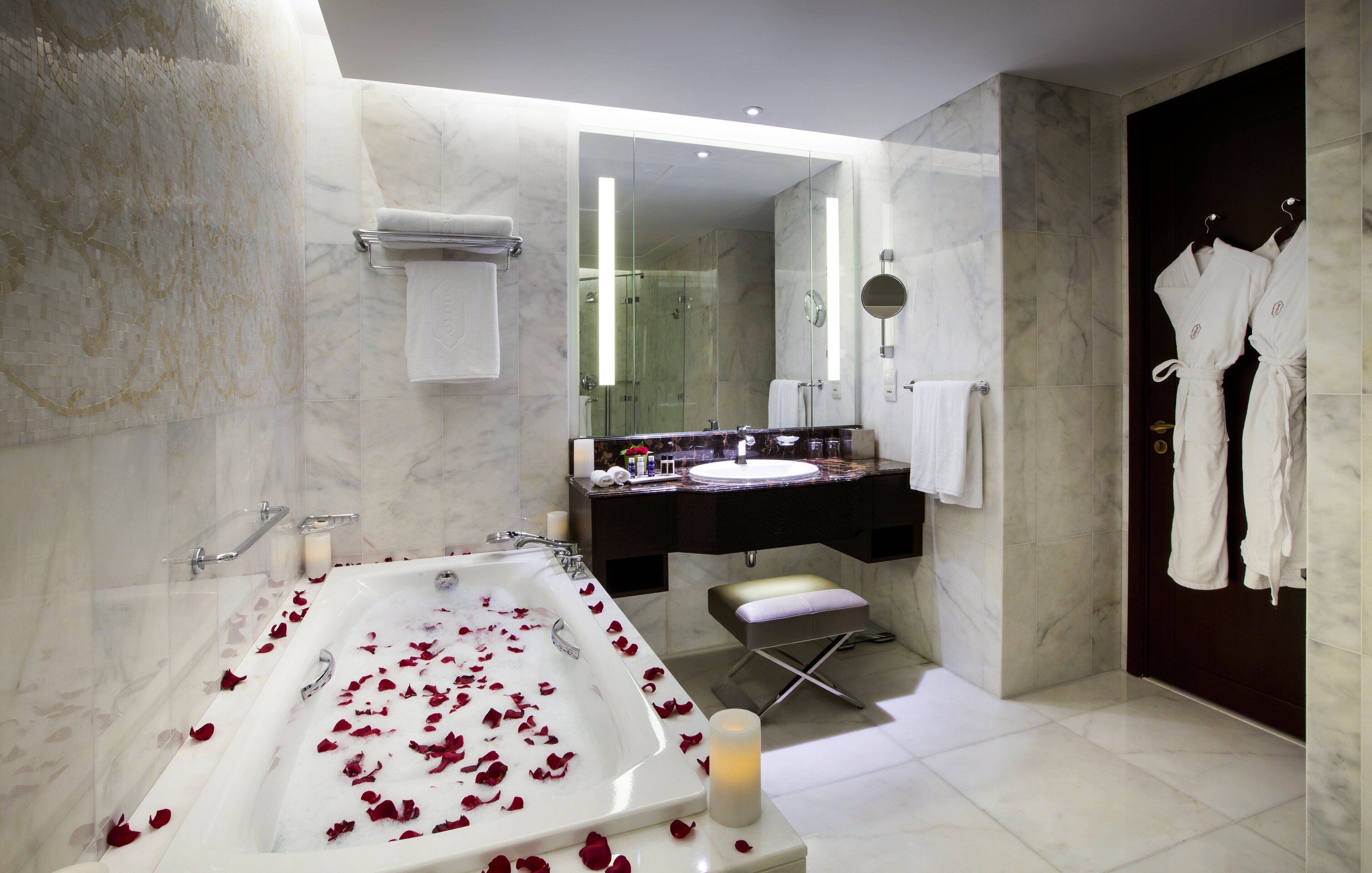 A modern bathroom with a large bathtub, a vanity with a mirror, and a robe rack.