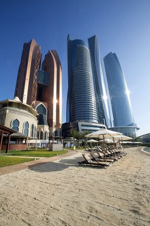 Privat strand, hvit sand, solsenger og parasoller