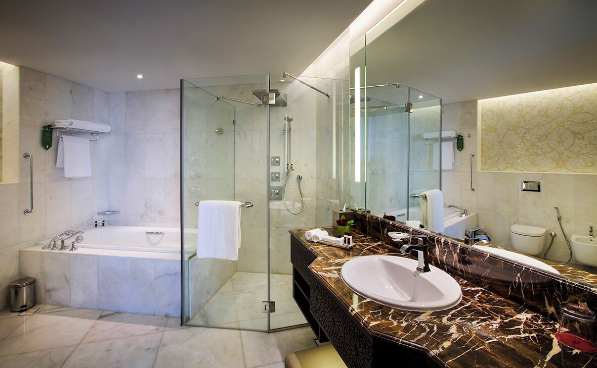 Une salle de bain moderne dotée d’une douche à parois de verre, d’une baignoire sur pieds et d’un meuble-lavabo avec un grand miroir.