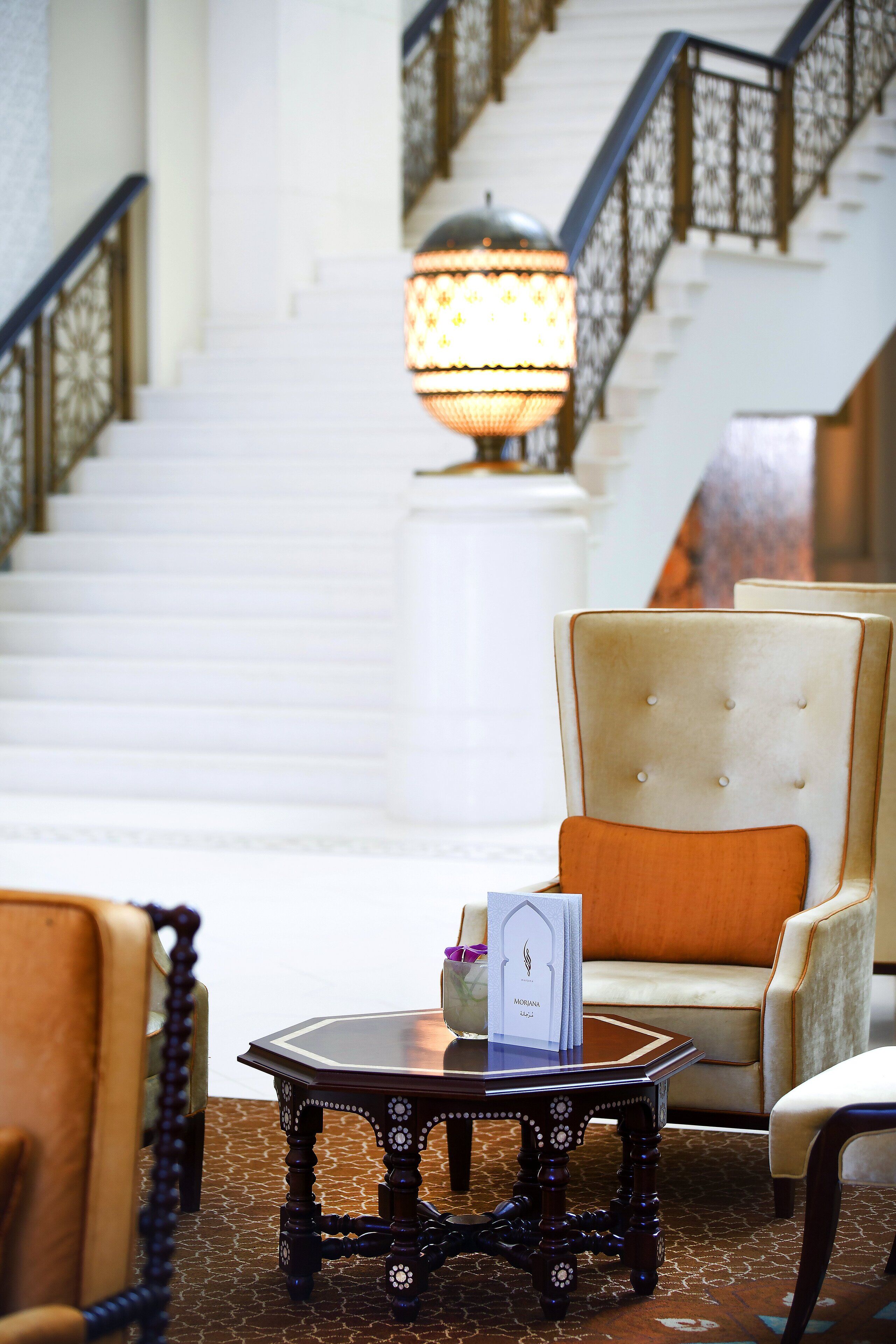 Eine Lobby mit Treppe, einem Tisch mit Lampe und einem Sessel.