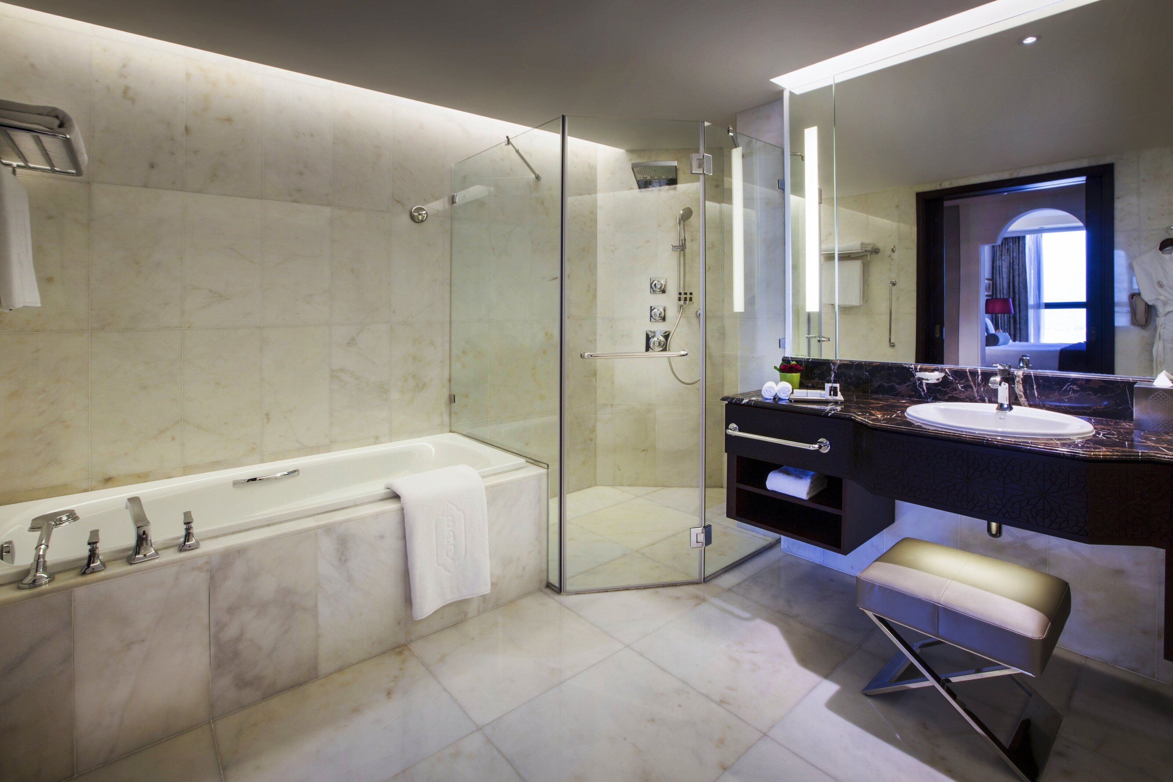 A modern bathroom with a glass-enclosed shower, a bathtub, a vanity with a sink, and a mirror.