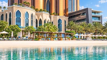 A beachfront hotel with a pool, palm trees, and modern architecture.