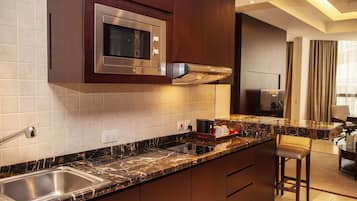 A modern kitchen with a built-in microwave, stainless steel sink, and marble countertop.