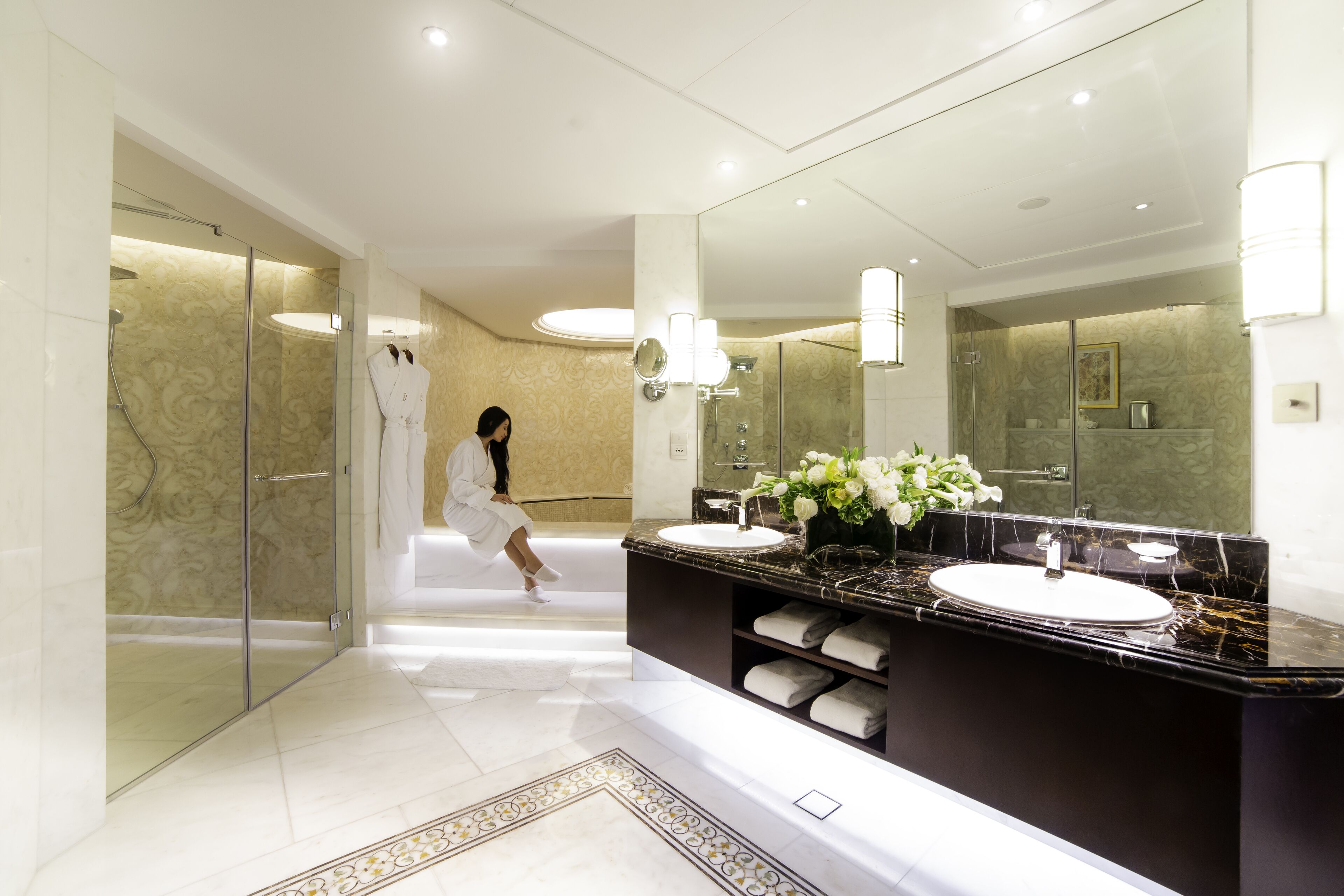 Ein modernes Badezimmer mit zwei Waschbecken, einem großen Spiegel und einer Duschkabine aus Glas.