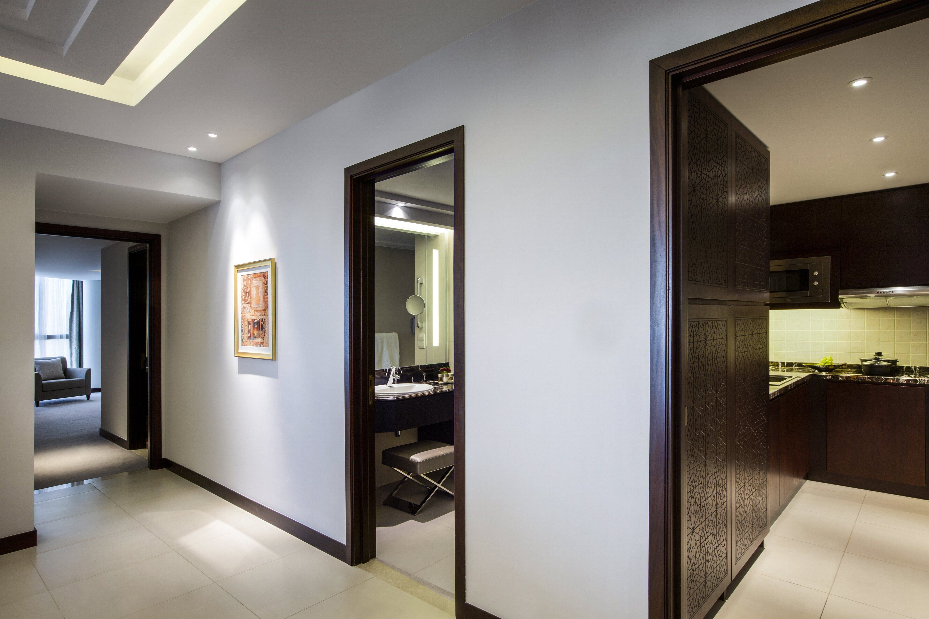 A modern interior with a hallway leading to a bathroom and a kitchen area.
