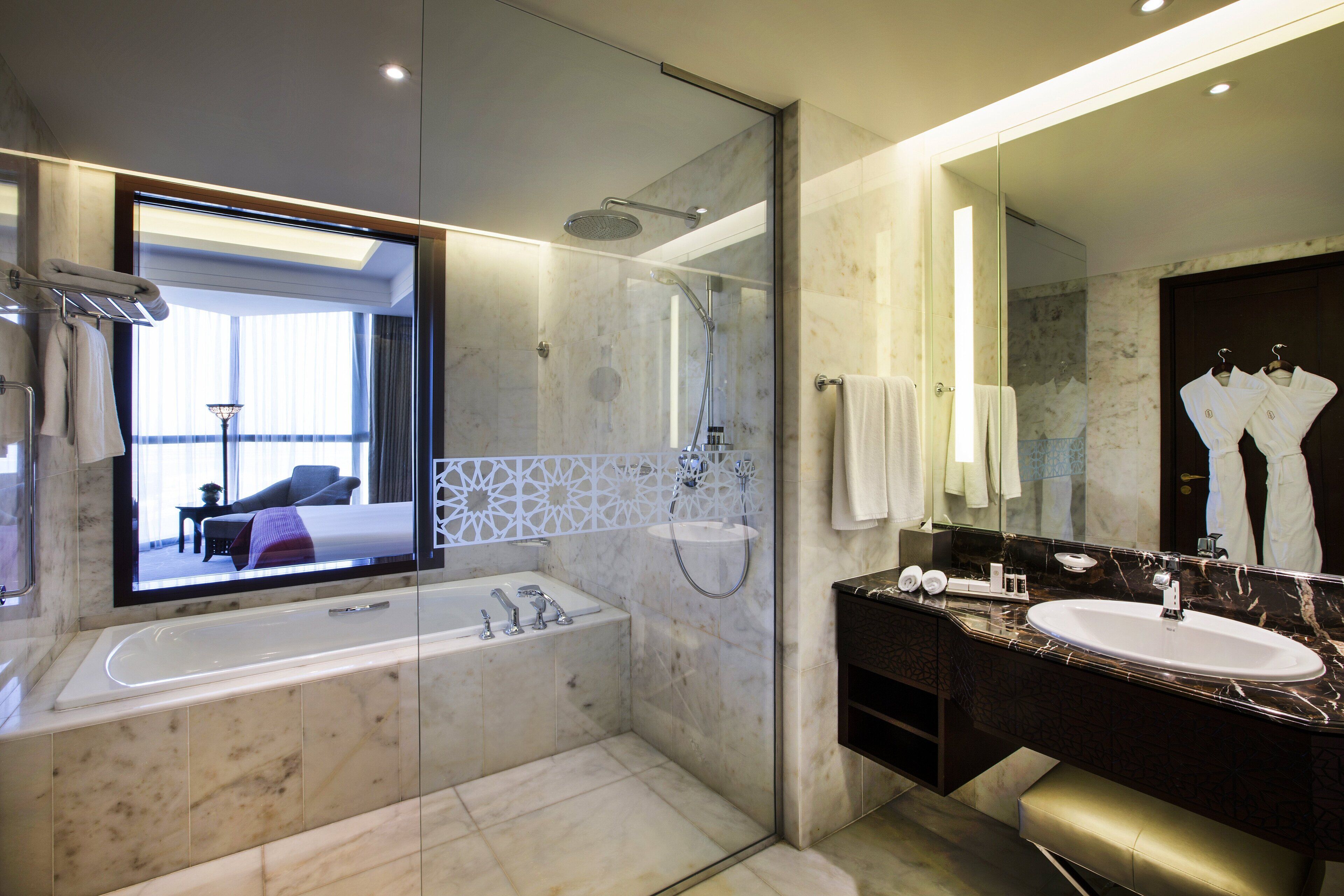 Un baño moderno con un espejo grande, una bañera y un lavamanos.