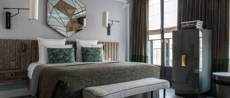 Una habitación de hotel moderna con una cama grande, un banco, un televisor y un mini bar.