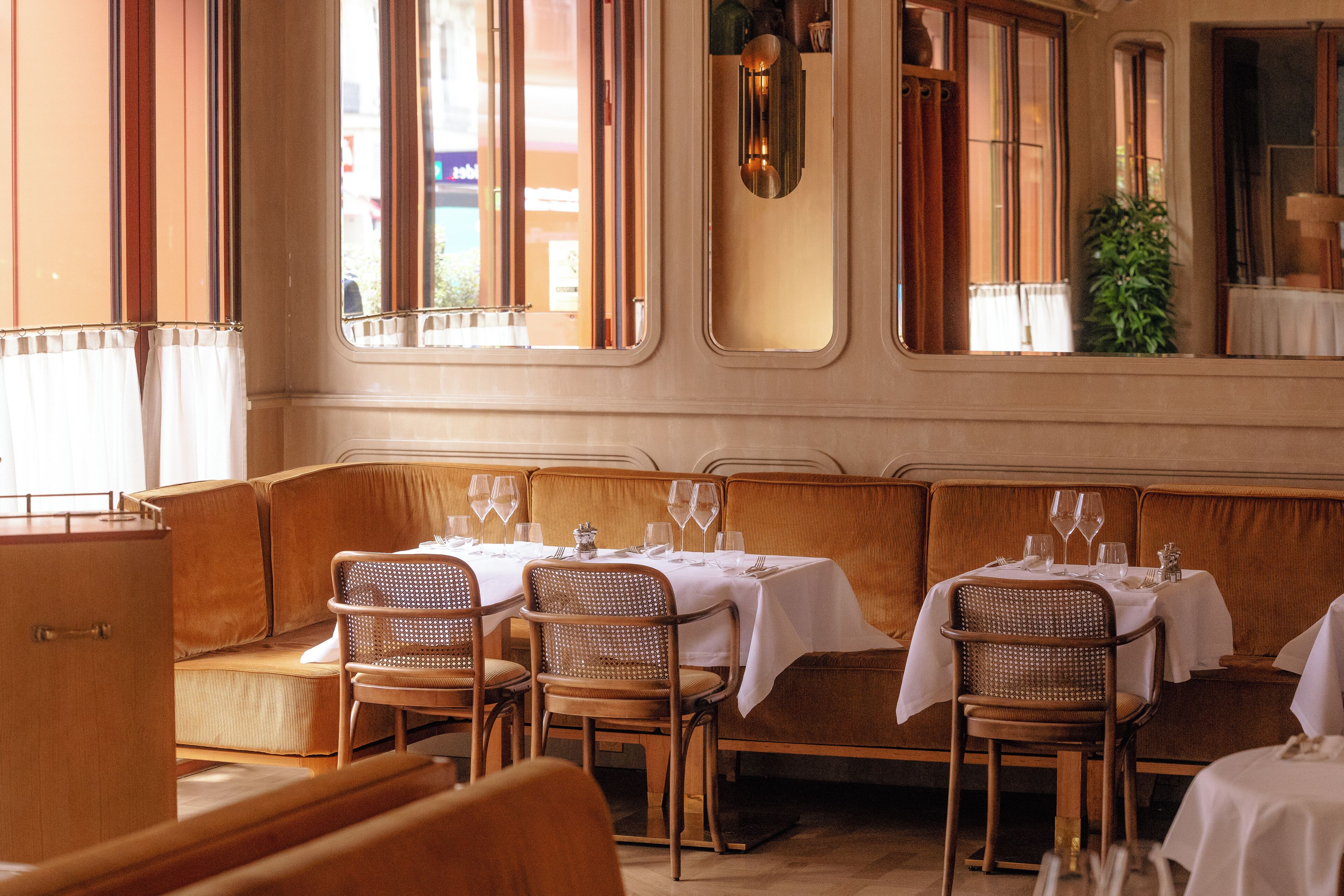 A restaurant interior with wooden booths, white tablecloths, and glassware.