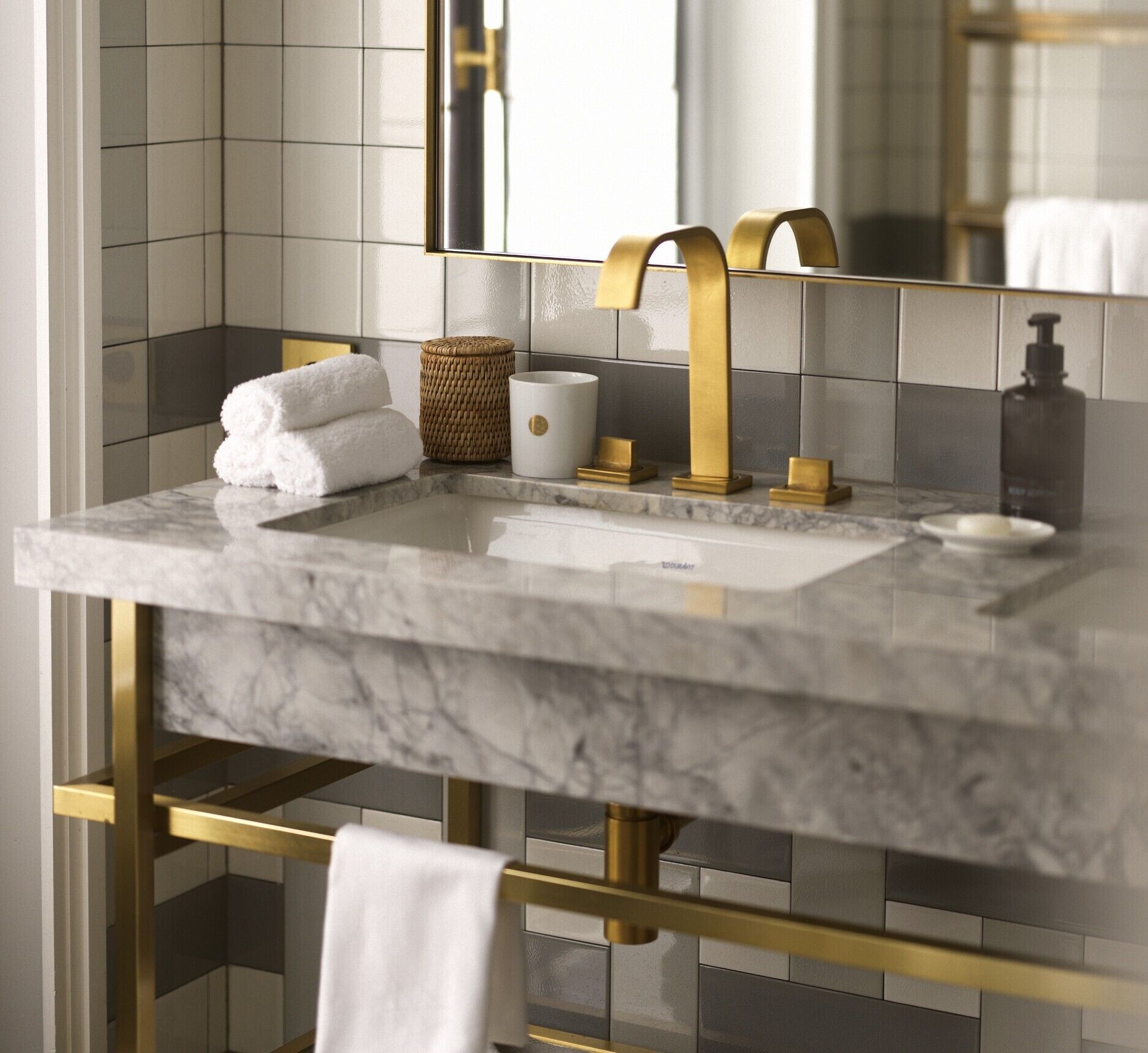 Une salle de bain avec un lavabo en marbre, des robinetteries dorées et un miroir.