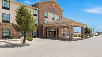 A hotel with a stone facade, a covered entrance, and a parking area.