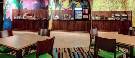 A restaurant with wooden paneling, a buffet counter, and green cushioned chairs.