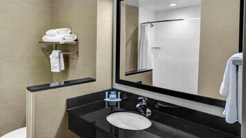 A modern bathroom with a black countertop sink, a large mirror, and a towel rack with folded towels.
