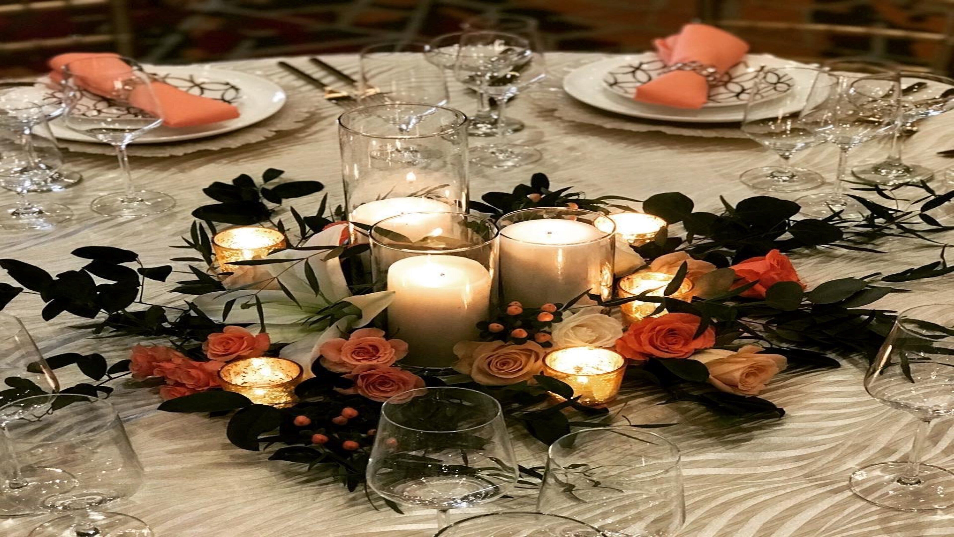 A table set with candles, glassware, and floral decorations.