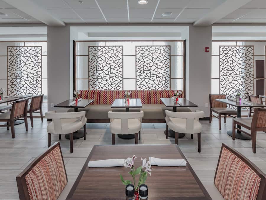 Restaurante com área de estar central, várias mesas e cadeiras.