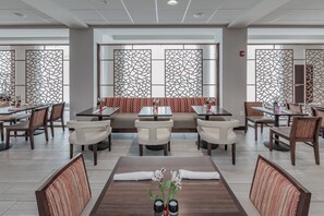 A restaurant with a central seating area, multiple tables, and chairs. - Holiday Inn Mishawaka by IHG (Mishawaka)