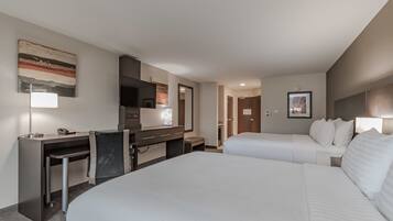A hotel room with a large bed, a desk with a chair, a TV, and a mirror.