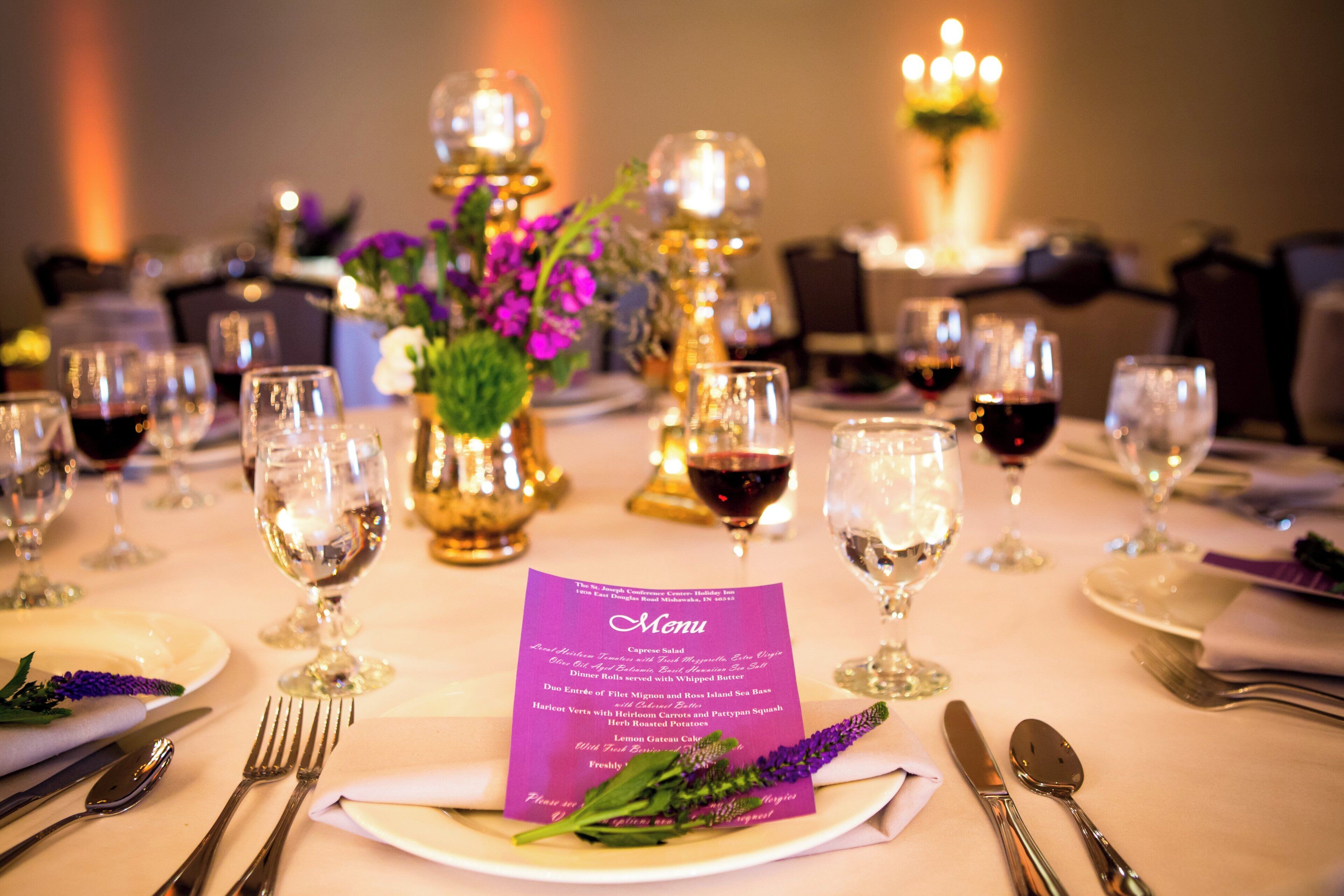 Une table mise pour un repas, avec un menu, des verres à vin et des couverts.