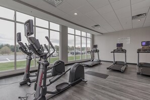 A gym with cardio equipment, large windows, and a sign about fitness center rules. - Holiday Inn Mishawaka by IHG (Mishawaka)