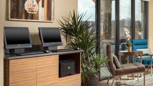 Un espace de bureau moderne équipé de deux écrans Dell, d’une imprimante, d’une grande plante en pot et d’un fauteuil en cuir.