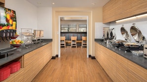 Une cuisine moderne avec des meubles en bois, un plan de travail noir et une vue sur la salle à manger.