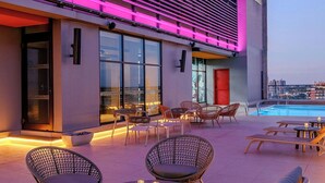 A modern hotel exterior with outdoor seating and a pool. - Aloft by Marriott Asuncion (Asunción)