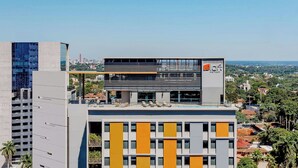 A modern hotel with a rooftop pool, multiple floors, and a view of the cityscape. - Aloft by Marriott Asuncion (Asunción)
