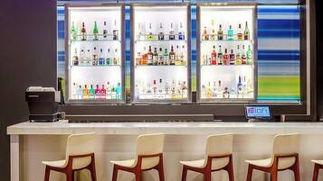 Eine Bar mit einer Neonreklame, mehreren Flaschenregalen und Barhocker.