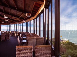 A restaurant with wicker furniture and large windows overlooking a body of water. - Lands End Boutique Hotel (Bluff)