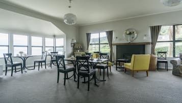 A spacious room with large windows, a fireplace, and a dining area with chairs and tables.