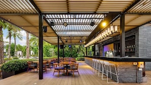 Une terrasse extérieure avec un sol en bois, des tables rondes et des chaises.