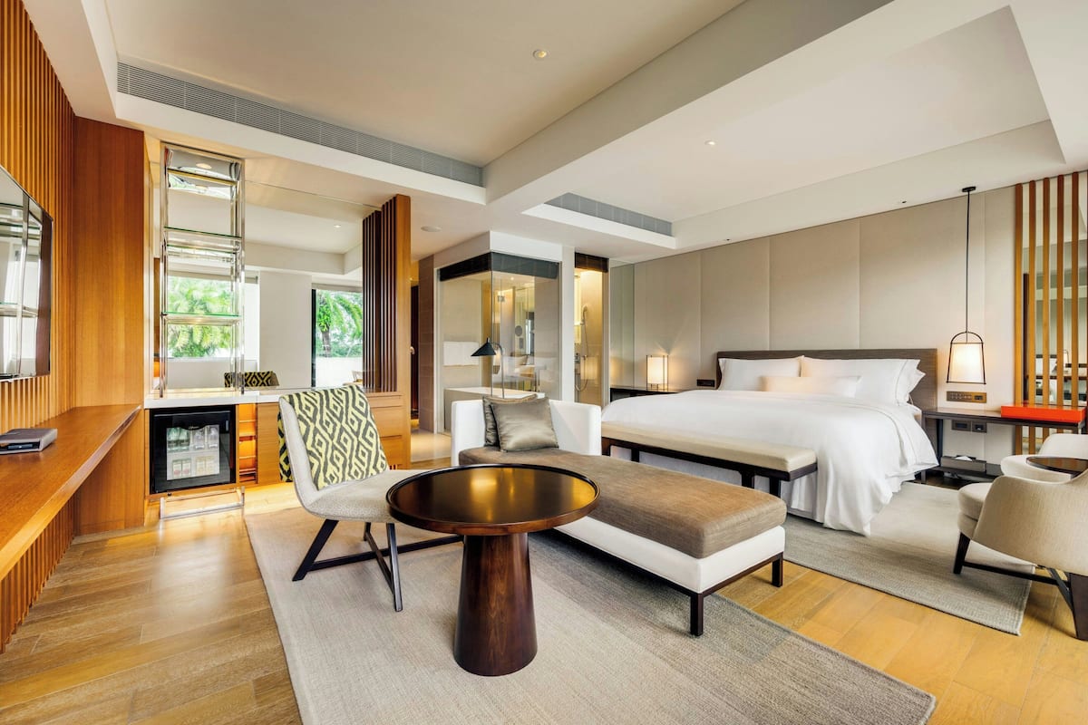 Ett modernt hotellrum med en stor säng, en soffa, ett runt soffbord och ett skrivbord med en dator.