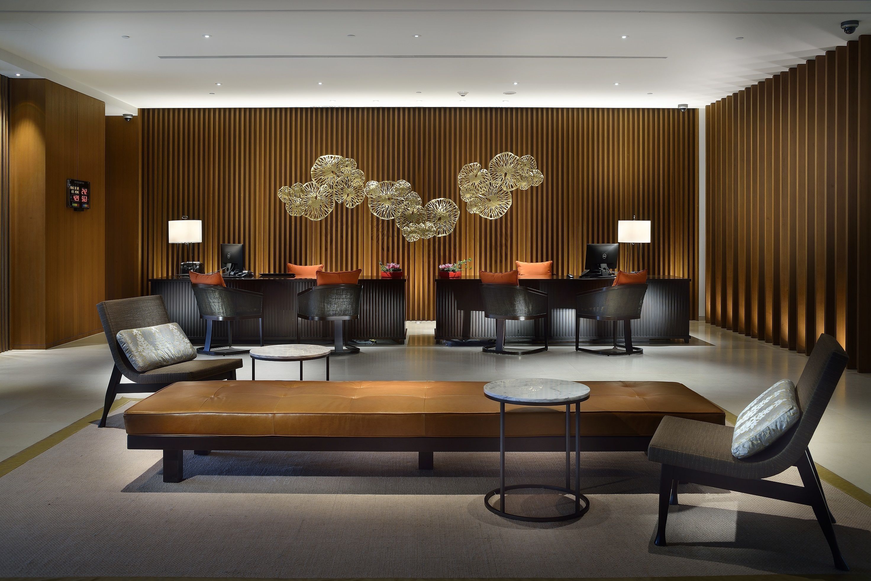 A modern lobby with a reception desk, seating area, and decorative wall panels.