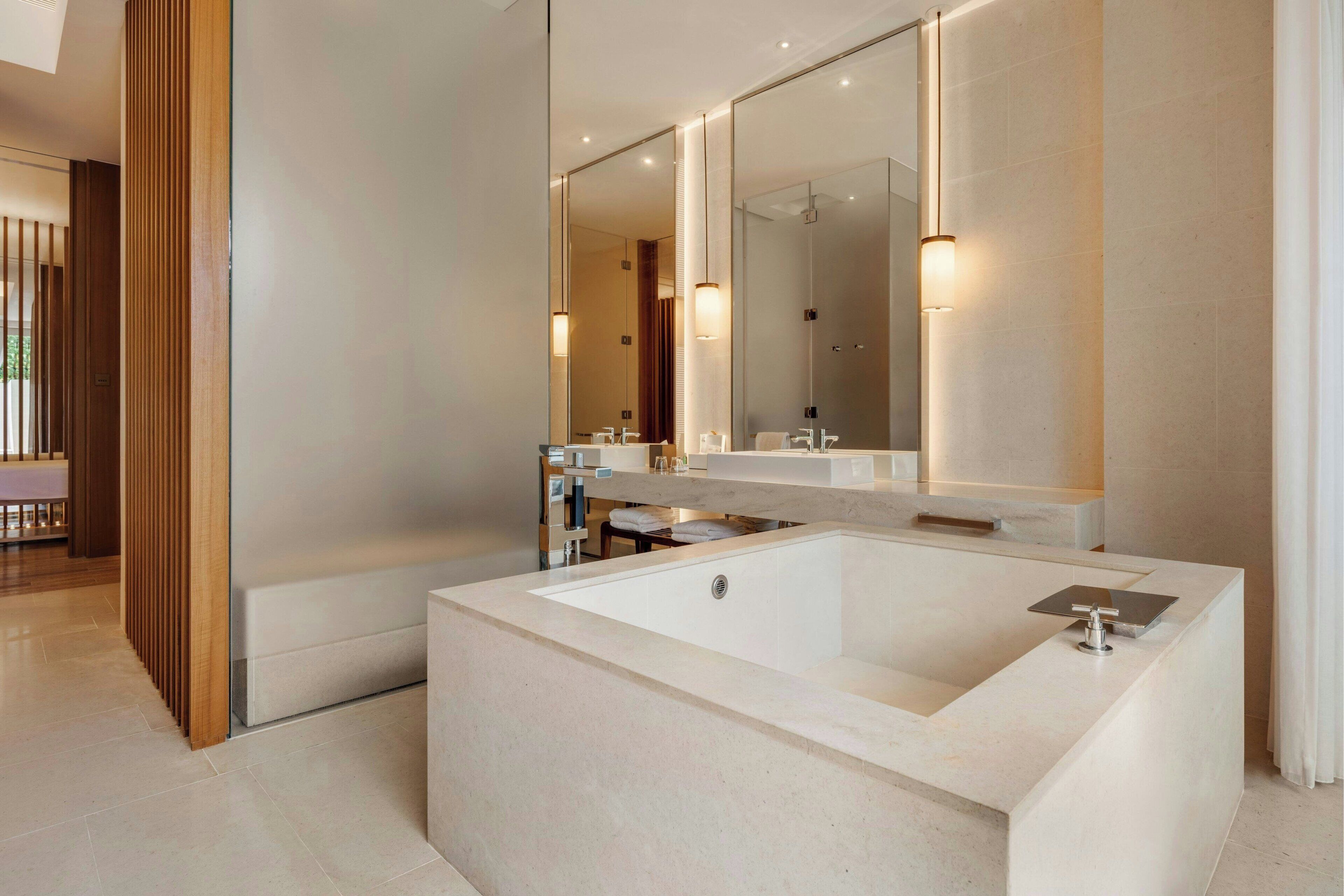 A modern bathroom with a large bathtub, a double sink vanity, and a large mirror.